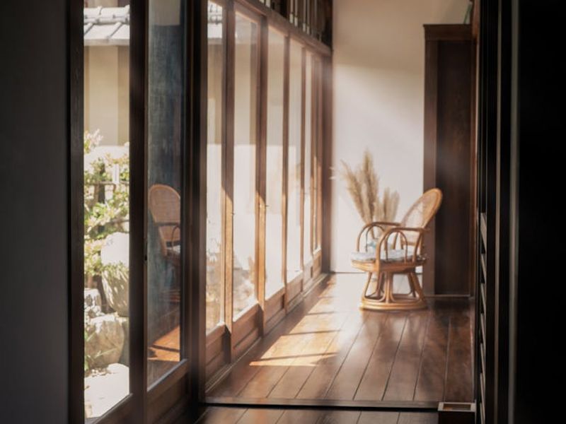 A large, bright yoga studio with wooden floors and large windows.